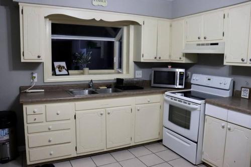 a kitchen with white cabinets and a sink and a microwave at The Little Amazon in Montgomery