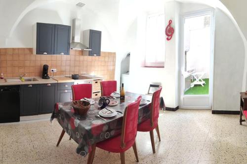 une cuisine avec une table à manger et des chaises rouges dans l'établissement le gite de flavie, à Montpeyroux