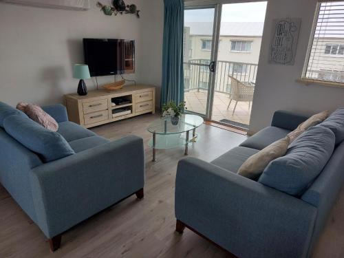 a living room with two blue couches and a television at Sandy Shores Holiday Units in Caloundra