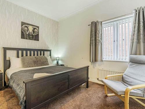 a bedroom with a bed and a chair and a window at Numero Uno Detached Aparthouse in Newcastle upon Tyne