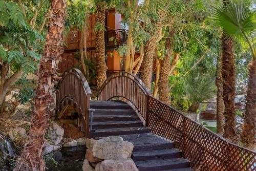a wooden staircase leading to a house with trees at Herbert Samuel Royal Shangri-La Eilat in Eilat
