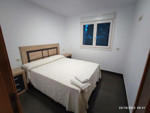 1 dormitorio con cama blanca y ventana en Casa con vistas a la Sierra de Guadarrama, en Guadarrama
