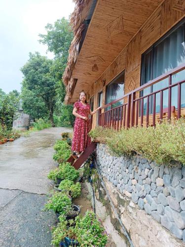 a woman in a dress standing next to a wall at Thao Ly Homestay Mai Chau in Hòa Bình