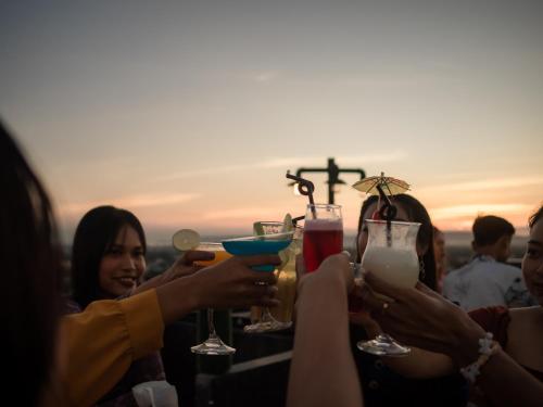 a group of people holding drinks at a rooftop bar at The Hotel Nova in Mandalay