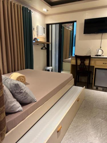 a bedroom with a bed and a desk with a computer at Palompon Sugar's Inn in Palompon