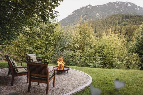 a fire pit with two chairs sitting around it with a view at Ferienwohnung Waldgarten in Leiten