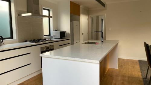 una cucina con banconi bianchi e piano di lavoro bianco di Newly built house a Lower Hutt