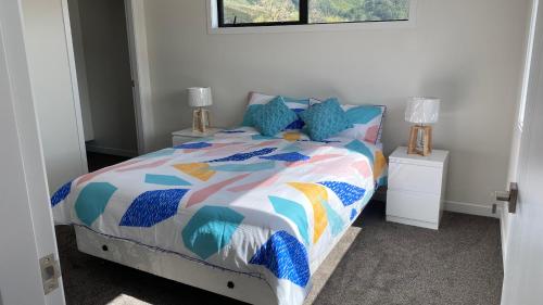ein Schlafzimmer mit einem Bett mit einer bunten Bettdecke in der Unterkunft Newly built house in Lower Hutt