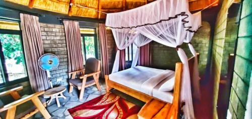 Gipir and Labongo Safari Lodge Ltd في Pakwach East: غرفة نوم بسرير مظلة وكرسي