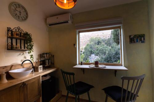 a bathroom with a sink and a window and two chairs at הפינה שלה -Hapina shella ראש פינה העתיקה in Rosh Pinna