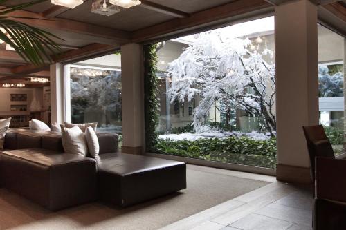 a living room with a large window with a chandelier at Palace Hotel Wellness & Beauty in Bormio