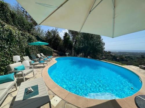 einen Pool mit Stühlen und einem Sonnenschirm in der Unterkunft Fantastic villa in the bay of Cannes, 5 minutes from the beach - with heated private pool in Mandelieu-la-Napoule