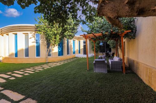 a backyard with chairs and a pergola and a building at Arjan Park Resorts in Riyadh