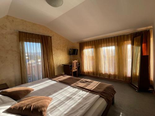 a bedroom with a large bed and windows at Meka Hotel in Dragash