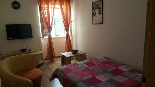 a bedroom with a bed and a chair and a window at Holiday Home Ana in Prvić Luka