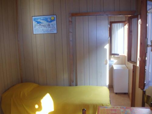 a small bedroom with a yellow bed and a window at Villaggio Camping Valdeiva in Deiva Marina