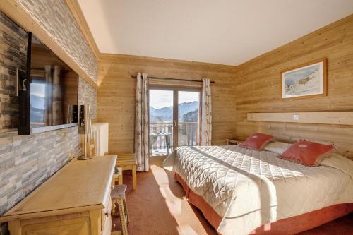 Schlafzimmer mit einem Bett, einem Schreibtisch und einem Fenster in der Unterkunft Le Castillan in L'Alpe-d'Huez