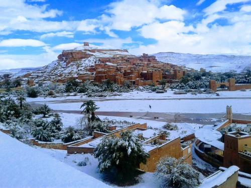 a city covered in snow with a mountain in the background at La Fibule D'or in Aït Ben Haddou