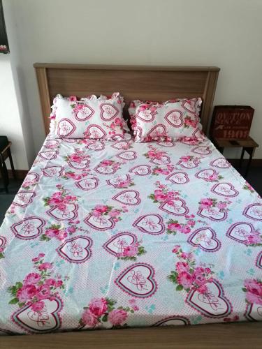 Una cama con una manta rosa de bienvenida y almohadas en Honey Guesthouse, en Pamplemousses Village