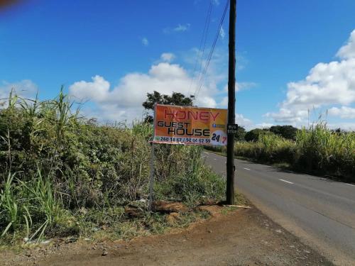 um sinal para uma casa na berma de uma estrada em Honey Guesthouse em Pamplemousses Village