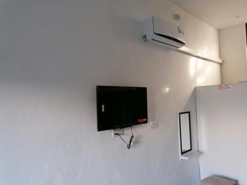 a flat screen tv hanging on a white wall at Honey Guesthouse in Pamplemousses Village