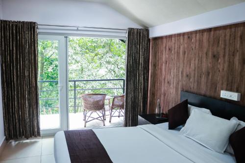 a hotel room with a bed and a balcony at Edens Munnar in Munnar