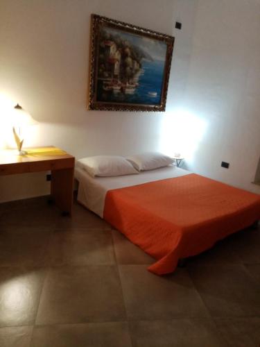 a bedroom with a bed with an orange blanket and a desk at La Casa di Antonella in Agrigento