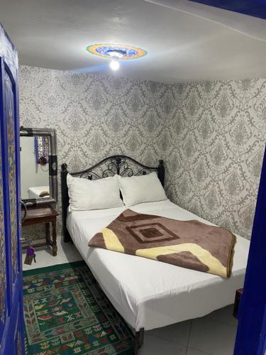 sypialnia z dużym łóżkiem z narzutą i obrazem w obiekcie Hostel Essassi 23 w Marakeszu