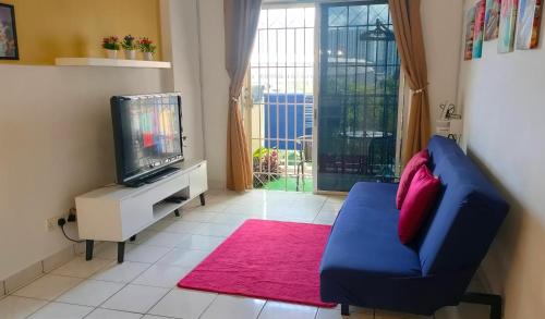 a living room with a blue couch and a tv at Apartment Next to Axiata Arena, Stadium Bukit Jalil in Kuala Lumpur