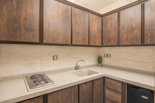 a kitchen with a sink and wooden cabinets at Roots Hotel in Makkah