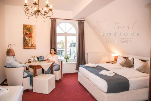 a man and woman sitting at a table in a hotel room at Stadtperle Rostock in Rostock