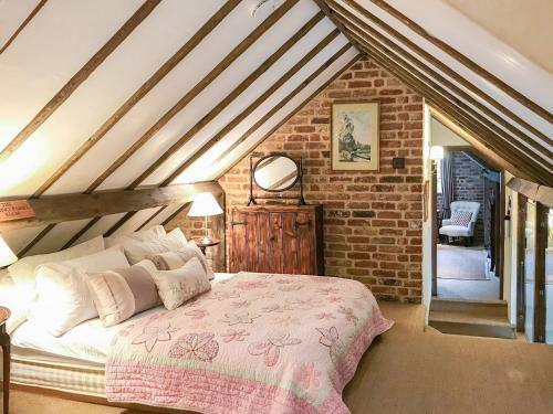 sypialnia z łóżkiem i ceglaną ścianą w obiekcie Old Rectory Barn w mieście Fernhurst