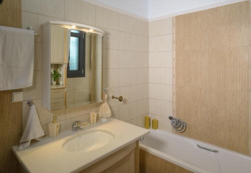 La salle de bains est pourvue d'un lavabo, d'une baignoire et d'un miroir. dans l'établissement Luxury Dafnis House, à Véria