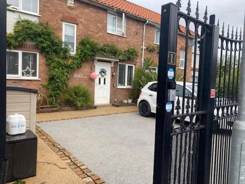 a car parked in front of a house with a gate at Willow Guest House in Norwich
