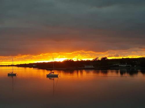 a sunset over a lake with boats in the water at 'Ar Y Tonnau' Y Felinheli Waterside Apartment in Y Felinheli