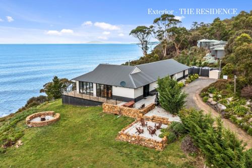 an aerial view of a house on a hill next to the ocean at Hamptons on the Bay in Swansea