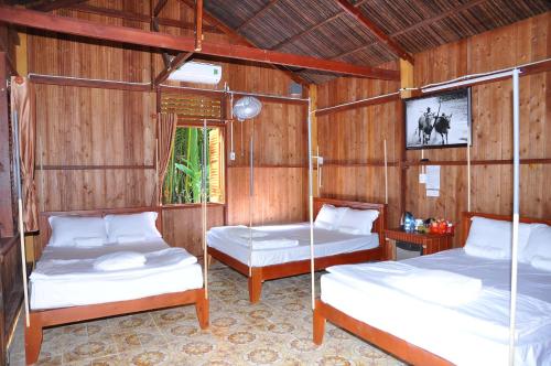 two beds in a room with wooden walls at Homestay Xóm Dừa Nước in Ben Tre