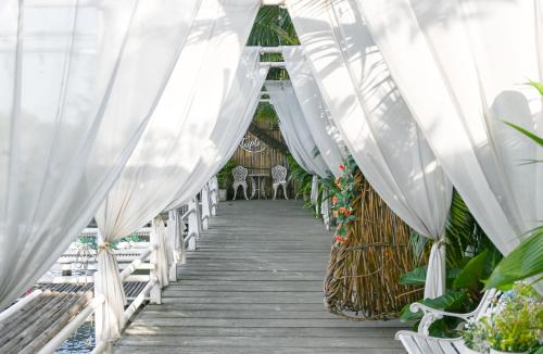 a wooden boardwalk with white drapes and chairs at Aranta Suvarnabhumi in Lat Krabang