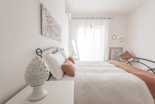a white bedroom with a bed and a vase on a table at Pappacoda 7 - Lecce Selection in Lecce