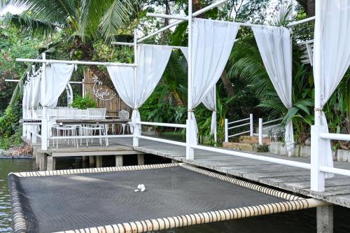a wooden dock with a table and chairs on the water at Aranta Suvarnabhumi in Lat Krabang