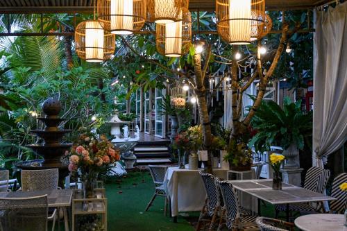 a restaurant with tables and chairs with plants and chandeliers at Aranta Suvarnabhumi in Lat Krabang