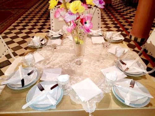 a table with plates and a vase of flowers on it at kasbah Dar Bahnini in Skoura