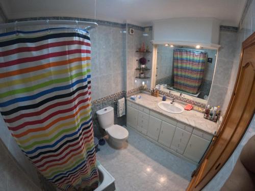 y baño con cortina de ducha colorida y aseo. en Comparte Espacio en Chiclana, en Chiclana de la Frontera