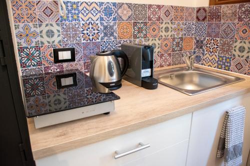 un bancone della cucina con macchinetta del caffè e lavandino di Maison L'amuri a Palermo