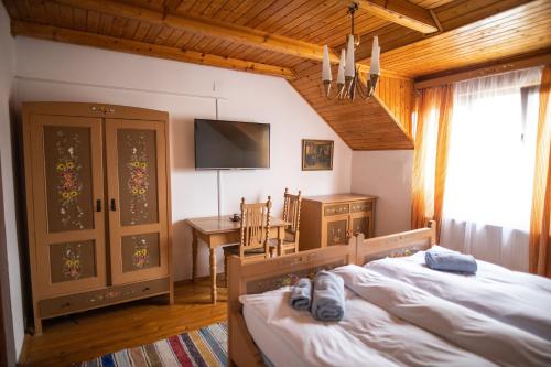 Un dormitorio con una cama, un escritorio y un televisor. en Pensiunea Sachsenhof, en BÄƒgaciu