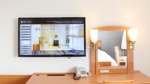 a tv on a wall with a welcome website at Imabari Urban Hotel in Imabari