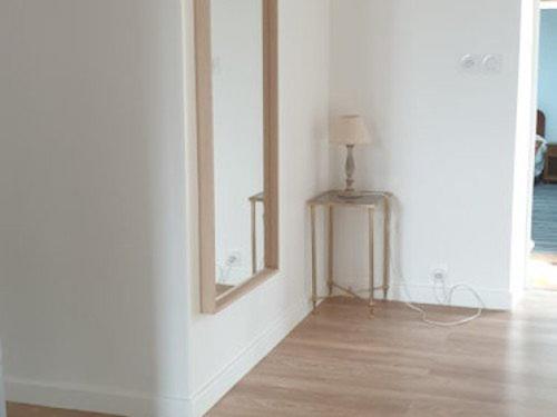 a room with a white wall and a table with a lamp at La Picardière in Perdreauville