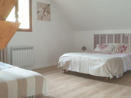a white bedroom with two beds and a wooden floor at La Picardière in Perdreauville