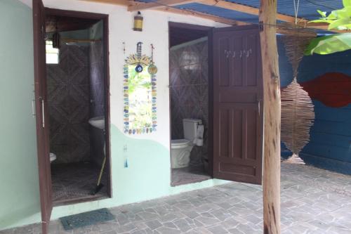 a bathroom with a toilet and an open door at Camping & Hostel Flor Do Cerrado in Ilha de Boipeba
