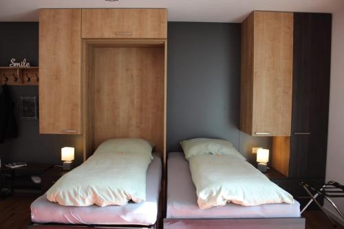 two beds in a room with wooden cabinets at Willy´s Ferienzimmer im Tabakdorf Hatzenbühl 